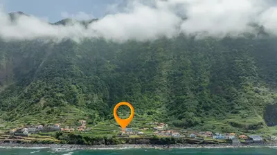 an orange kite flying over a village on a mountain at Coastal São Vicente Mountain & Sea View Hideaway with Free Parking in São Vicente