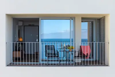 a balcony with a view of a pool and the ocean at Atlantic Nest Apartment by Holiday Rental Madeira in Câmara de Lobos