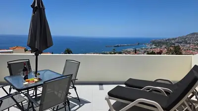 a patio with lounge chairs and an umbrella at Santa Maria Villa in Funchal
