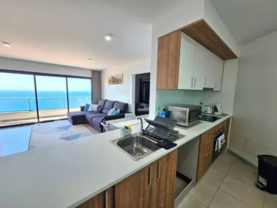 a kitchen with a counter top and a living room at Garajau Residence Sea View by Rentallido in Caniço
