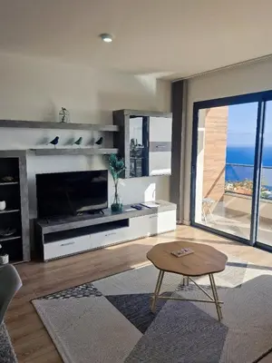 a living room with a large television and a table at Garajau Residence Sea View by Rentallido in Caniço