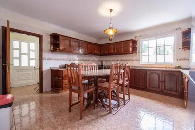 a kitchen with wooden cabinets and a table and chairs at Recanto do Estreito by GALMI in Estreito da Calheta