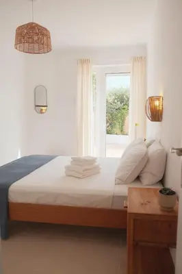 a bedroom with a bed with white sheets and a window at Algarve Windmill, Villa and Pool 2000m to the Beach in Figueira