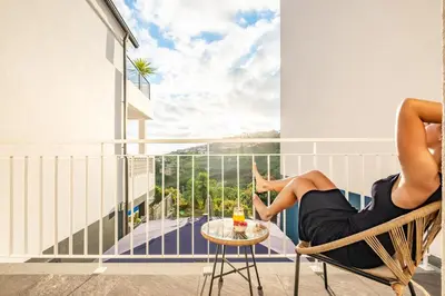 a woman sitting in a chair on a balcony with a table at Marrom Mystique in Canhas