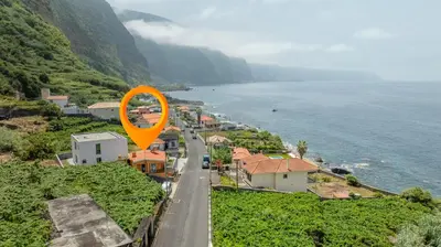 a orange sign on a road next to the ocean at Scenic Home with Panoramic Sea & Mountain Views in São Vicente in São Vicente