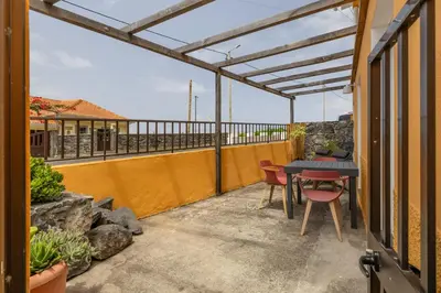 a patio with a table and chairs on a balcony at Scenic Home with Panoramic Sea & Mountain Views in São Vicente in São Vicente