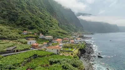 a village on the side of a mountain next to the water at Scenic Home with Panoramic Sea & Mountain Views in São Vicente in São Vicente