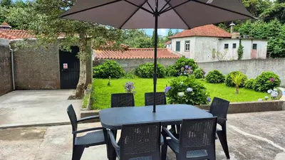 a table and chairs with an umbrella in a yard at Chalé da Serra in Santo da Serra