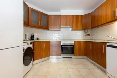 a kitchen with wooden cabinets and a washer and dryer at Porto de Abrigo in Burgau