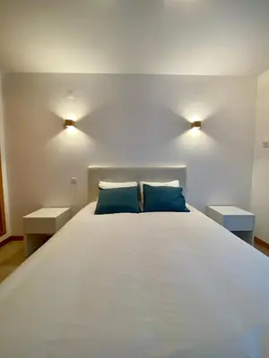 a bedroom with a large white bed with blue pillows at Porto de Abrigo in Burgau