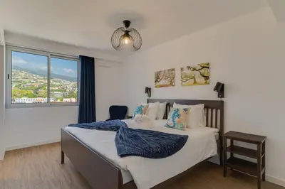 a bedroom with a bed with a blue blanket on it at Pearl Retreat by Holiday Rental Madeira in Câmara de Lobos