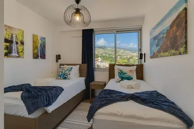 a bedroom with two beds and a large window at Pearl Retreat by Holiday Rental Madeira in Câmara de Lobos