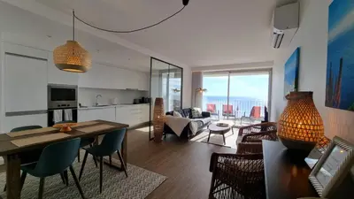 a kitchen and living room with a table and chairs at Pearl Retreat by Holiday Rental Madeira in Câmara de Lobos