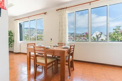 a dining room with a table and chairs and windows at Casa do Pico by Atlantic Holiday in Câmara de Lobos