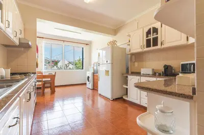 a large kitchen with white appliances and a table at Casa do Pico by Atlantic Holiday in Câmara de Lobos