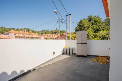 a balcony with a white wall and a stove at Joana's House in Camacha