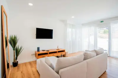 a white living room with a couch and a tv at Joana's House in Camacha