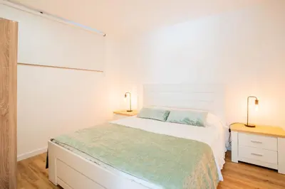 a white bedroom with a bed and two lamps at Joana's House in Camacha