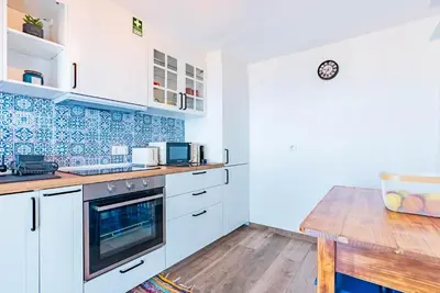 a kitchen with white cabinets and a wooden table at Casa D'Avó Bela in Arco da Calheta