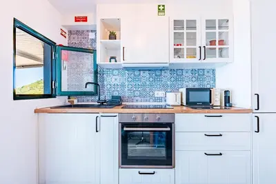 a kitchen with white cabinets and a sink and an oven at Casa D'Avó Bela in Arco da Calheta