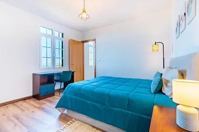 a bedroom with a blue bed and a desk at Casa D'Avó Bela in Arco da Calheta