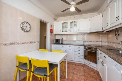 a kitchen with a white table and yellow chairs at Lovely beach apartment, sea views, rooftop terrace #1974 in Budens
