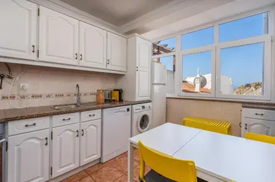 a kitchen with white cabinets and a table and chairs at Lovely beach apartment, sea views, rooftop terrace #1974 in Budens