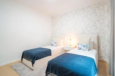 two beds in a white room with blue sheets at Nora Charming Apartment - Pool -10m Walk City Center in Funchal