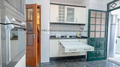 a kitchen with white cabinets and a green door at Machico Village by LovelyStay in Machico