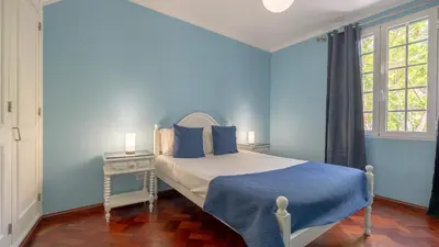 a blue bedroom with a bed and a window at Machico Village by LovelyStay in Machico