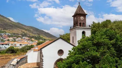 a white church with a clock tower on a hill at Machico Village by LovelyStay in Machico