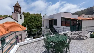 a patio with chairs and a table and a clock tower at Machico Village by LovelyStay in Machico