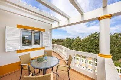 a patio with a glass table and chairs on a balcony at Villa Ruby in Budens