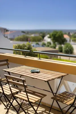 a wooden table and two chairs on a balcony at Sagres ZEN - 3 Bedroom House in Sagres