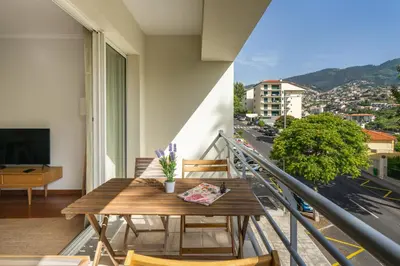 a balcony with a table and chairs and a view of a city at OurMadeira - Madalena Living Apt in Funchal