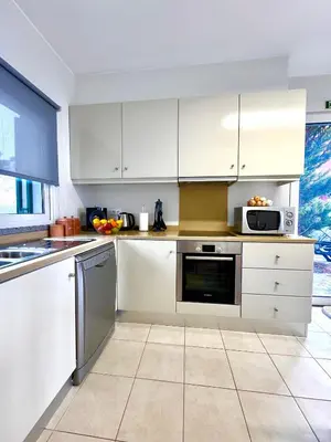 a white kitchen with white cabinets and appliances at Sunset Dreams - Arco da Calheta in Arco da Calheta