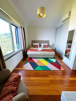 a bedroom with a bed and a colorful rug on the floor at Sunset Dreams - Arco da Calheta in Arco da Calheta