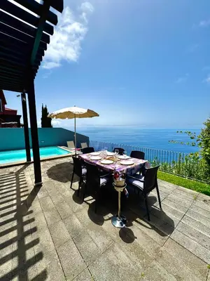 a table with chairs and an umbrella on a patio at Sunset Dreams - Arco da Calheta in Arco da Calheta