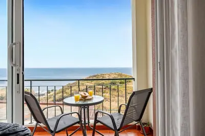 a balcony with a table and chairs and a view of the ocean at Pérola Apartments by YOUR KEY in Caniço