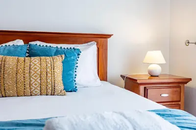 a bedroom with a bed with blue and white pillows at Pérola Apartments by YOUR KEY in Caniço