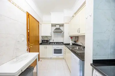 a kitchen with white cabinets and a stove top oven at Pérola Apartments by YOUR KEY in Caniço