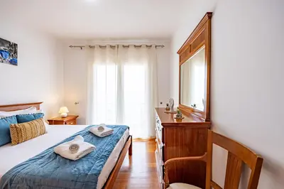 a bedroom with a bed and a dresser and a mirror at Pérola Apartments by YOUR KEY in Caniço