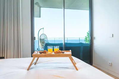 a table with two glasses of orange juice and donuts on a bed at Seaside Escape by Atlantic Holiday in Funchal