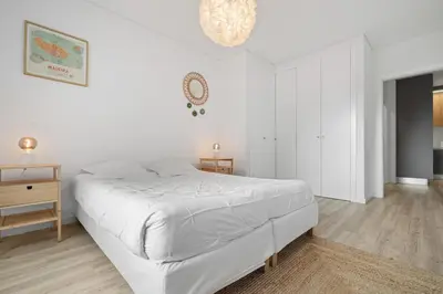 a white bedroom with a bed and a clock on the wall at MK Apart I in Funchal