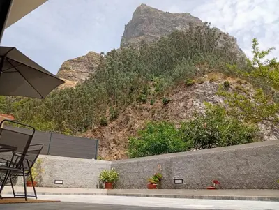 a table and chairs with a mountain in the background at Danny's Rural Suite T2 in Curral das Freiras