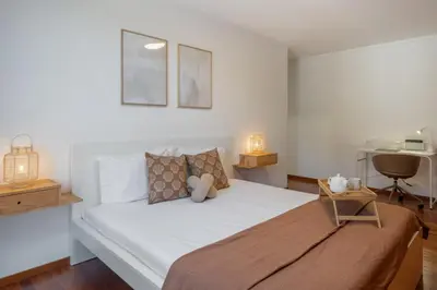 a bedroom with a bed with white sheets and a chair at Wings Apartment II by An Island Apart in Santa Cruz