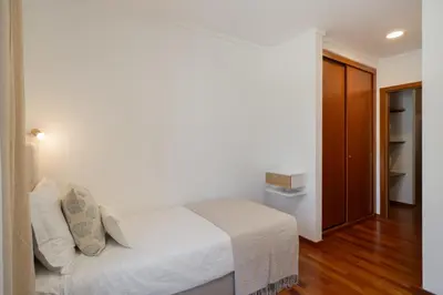 a bedroom with a white bed and a wooden floor at Wings Apartment II by An Island Apart in Santa Cruz
