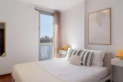 a white bedroom with a bed and a window at Wings Apartment II by An Island Apart in Santa Cruz
