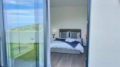 a bedroom with a bed and a sliding glass door at The Barreto's Clive in Ponta do Sol