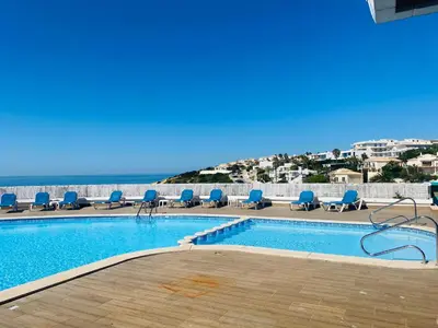 a swimming pool with chairs and the ocean in the background at Magnolia Studio 303 in Lagos